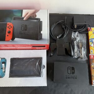 Nintendo Switch package with console, dock, neon red/blue Joy‑Con controllers, and accessories laid out beside two game boxes (Sonic Mania and Rayman Legends)